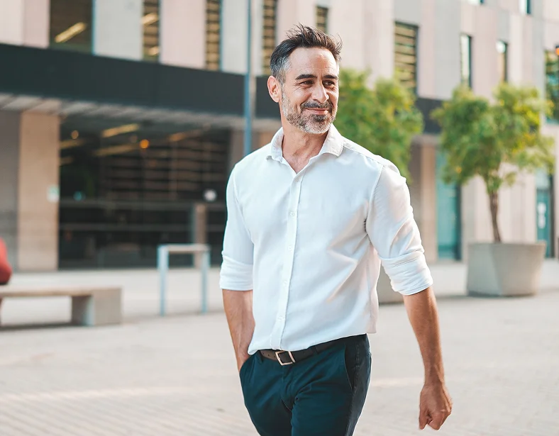 Professional man in white shirt walking confidently outdoors in urban business district setting - in Owings Mills, MD