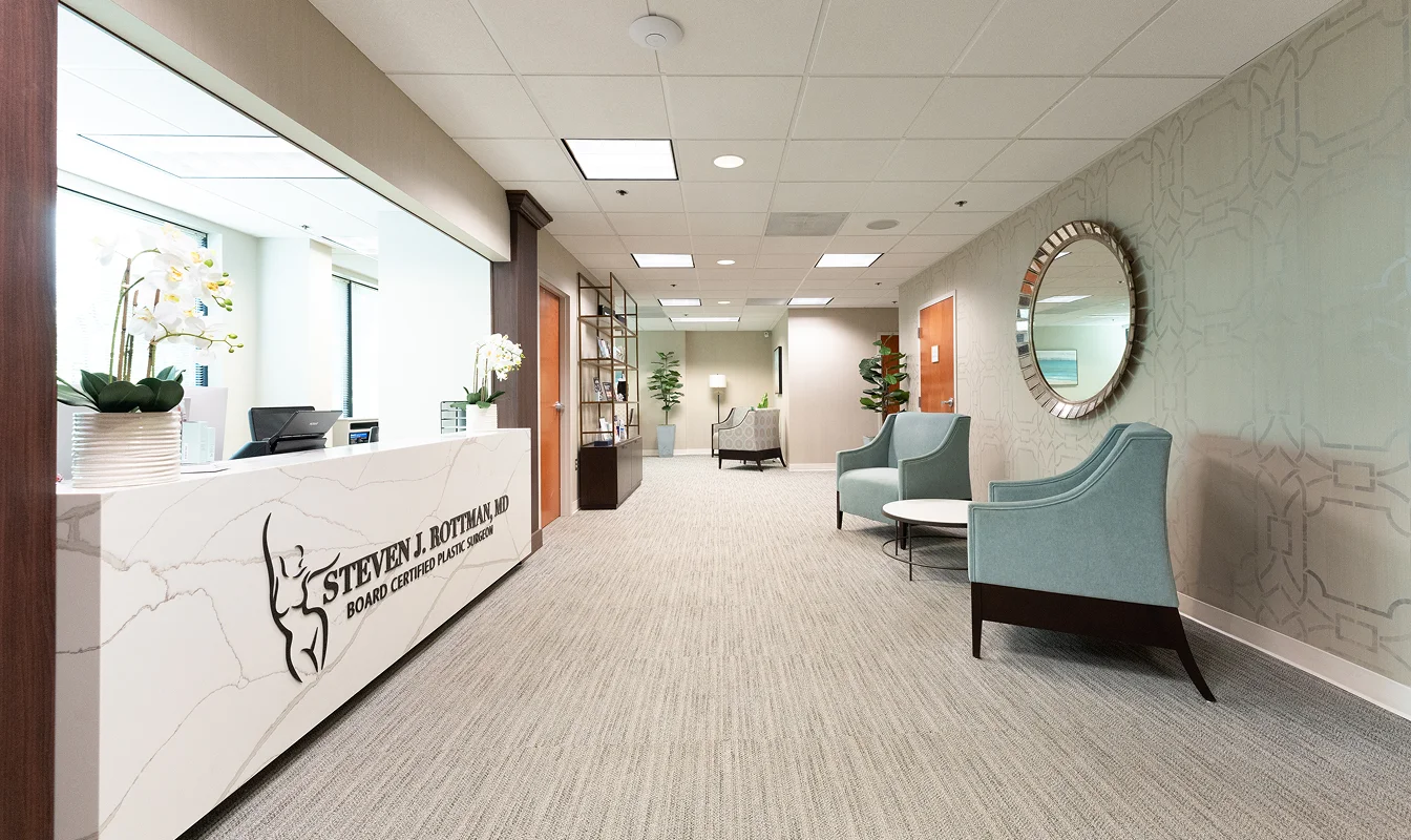 Modern dental office reception area with blue chairs, round mirror, and bright natural lighting