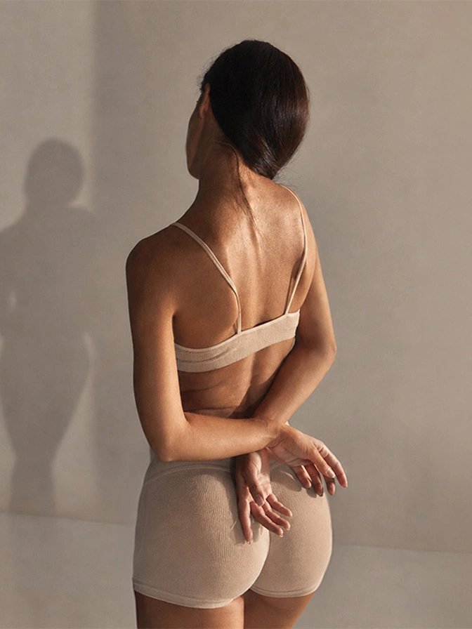 Woman wearing beige bandeau top and shorts set viewed from behind against neutral background - Brazilian butt lift in Owings Mills, MD
