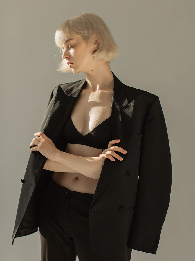 Blonde woman in black blazer and bralette with minimalist styling against neutral background - Breast lift in Owings Mills, MD