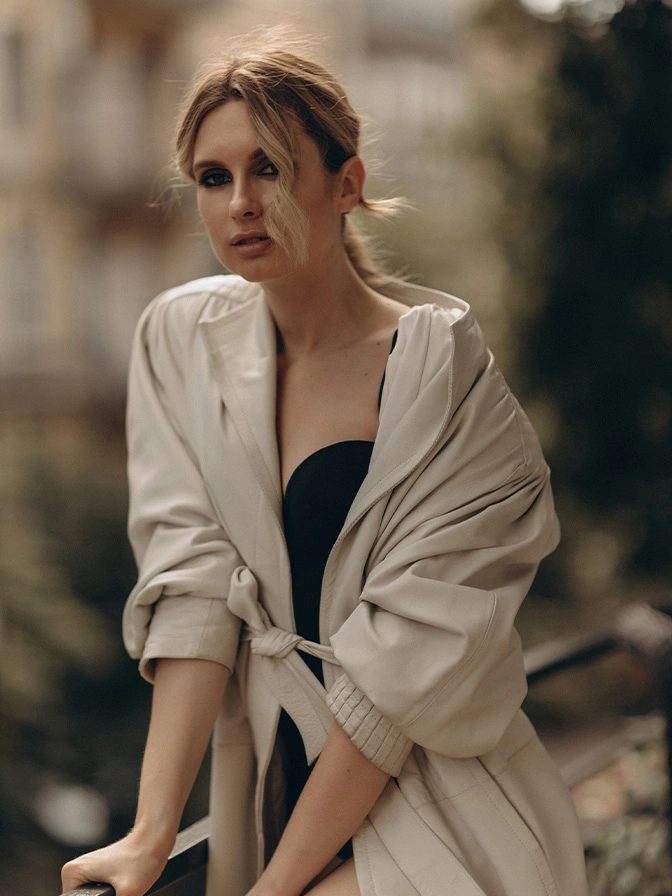 Woman in black top and beige linen shirt with natural makeup and hair in bun, outdoor portrait - Fat transfer breast augmentation in Owings Mills, MD