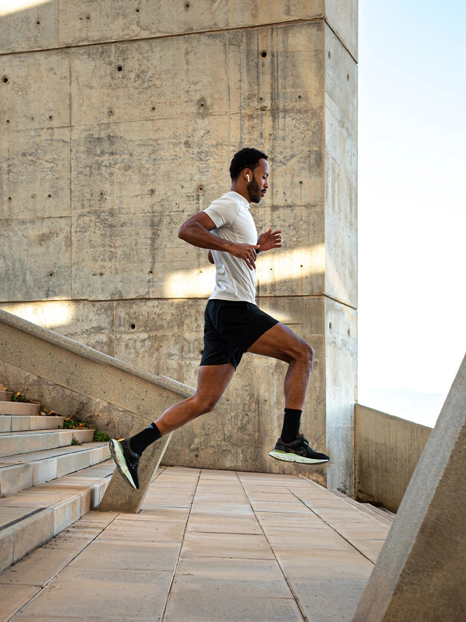 Athletic man running up concrete stairs outdoors during workout training session - Lower body lift in Owings Mills, MD