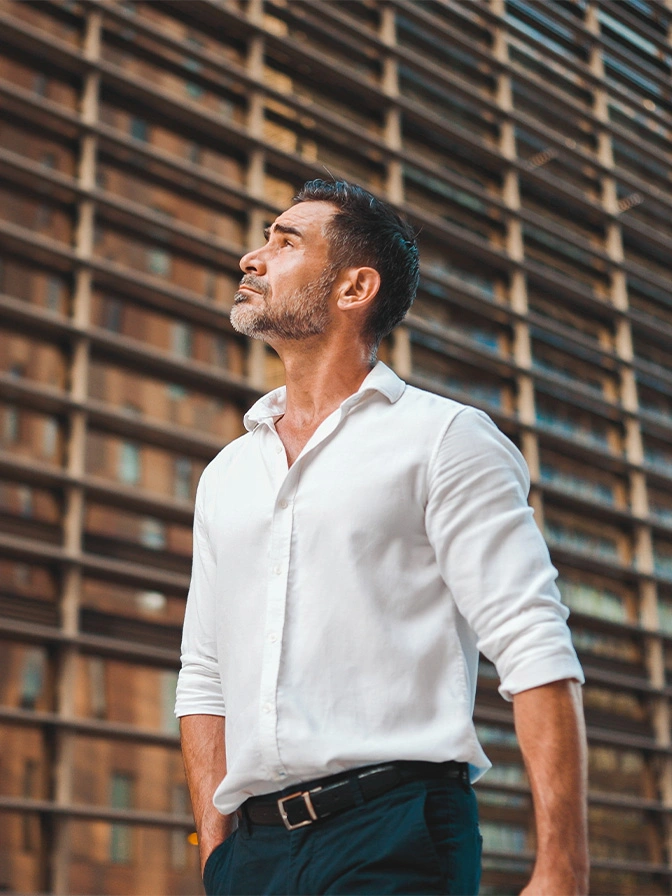 Professional man in white shirt looking up confidently against modern building backdrop - Post weight loss surgery in Owings Mills, MD