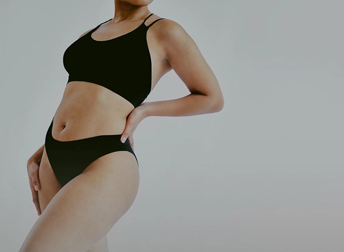 Woman wearing dark green sports bra and high-waisted underwear set against neutral background - post weight in Owings Mills, MD