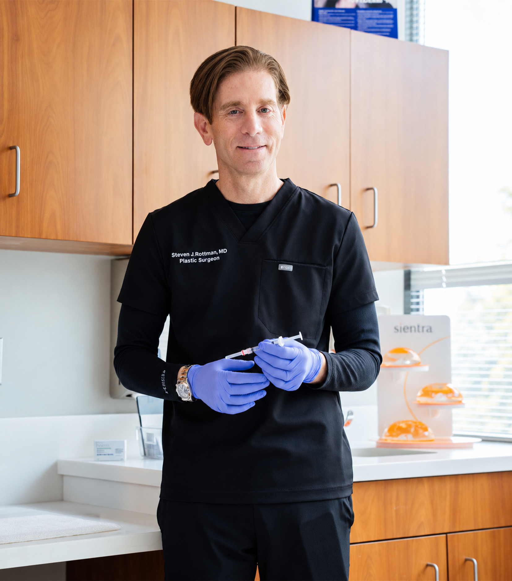 Dr Rottman MD in black lab coat wearing blue gloves standing in modern laboratory with wooden cabinets - in Owings Mills, MD